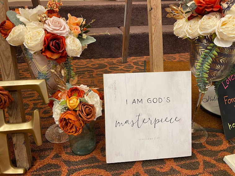 I am God's masterpiece is written on this beautiful sign surrounded by flowers at the Fireweed Birth Mom Retreat